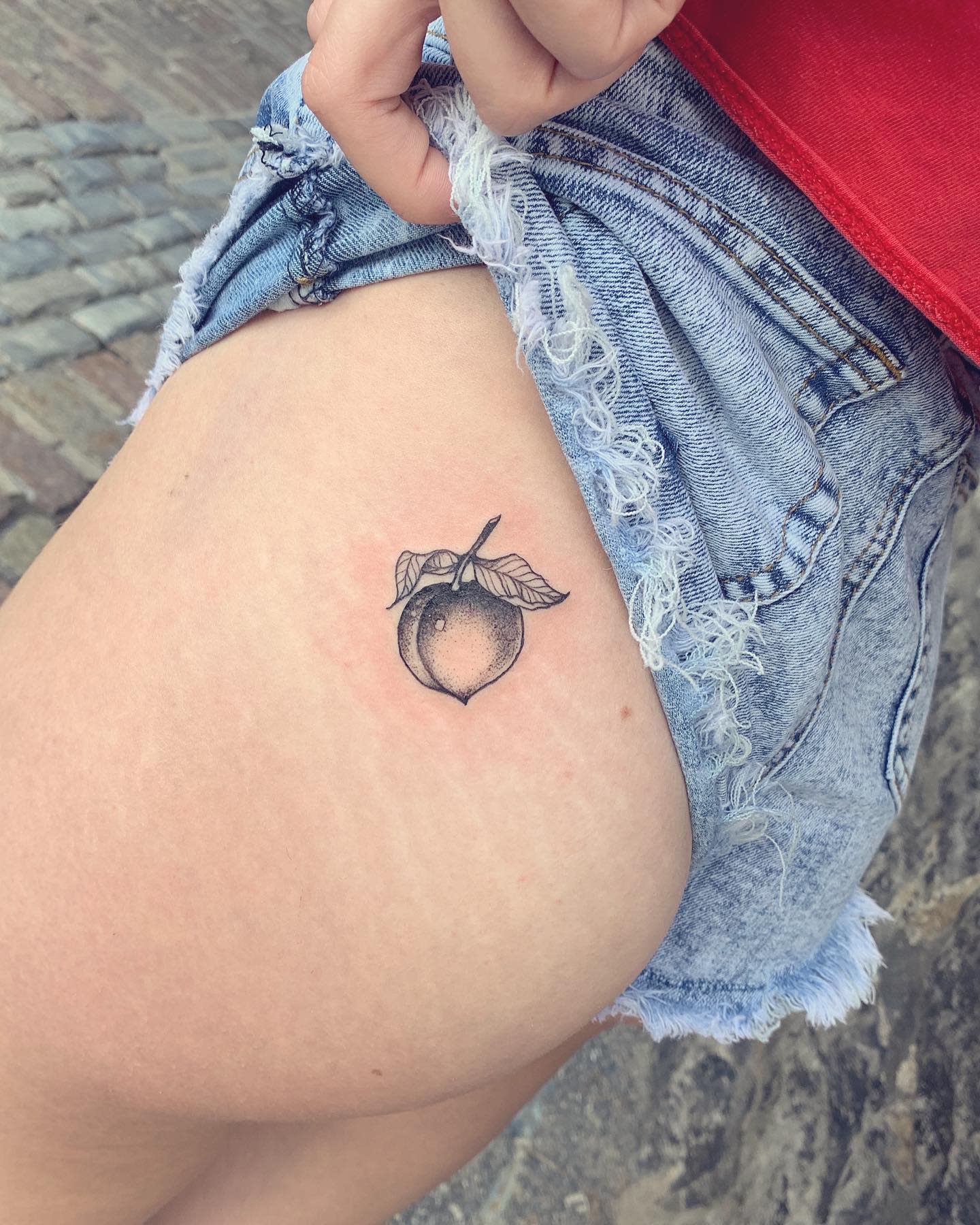 Small peach tattoo on upper thigh